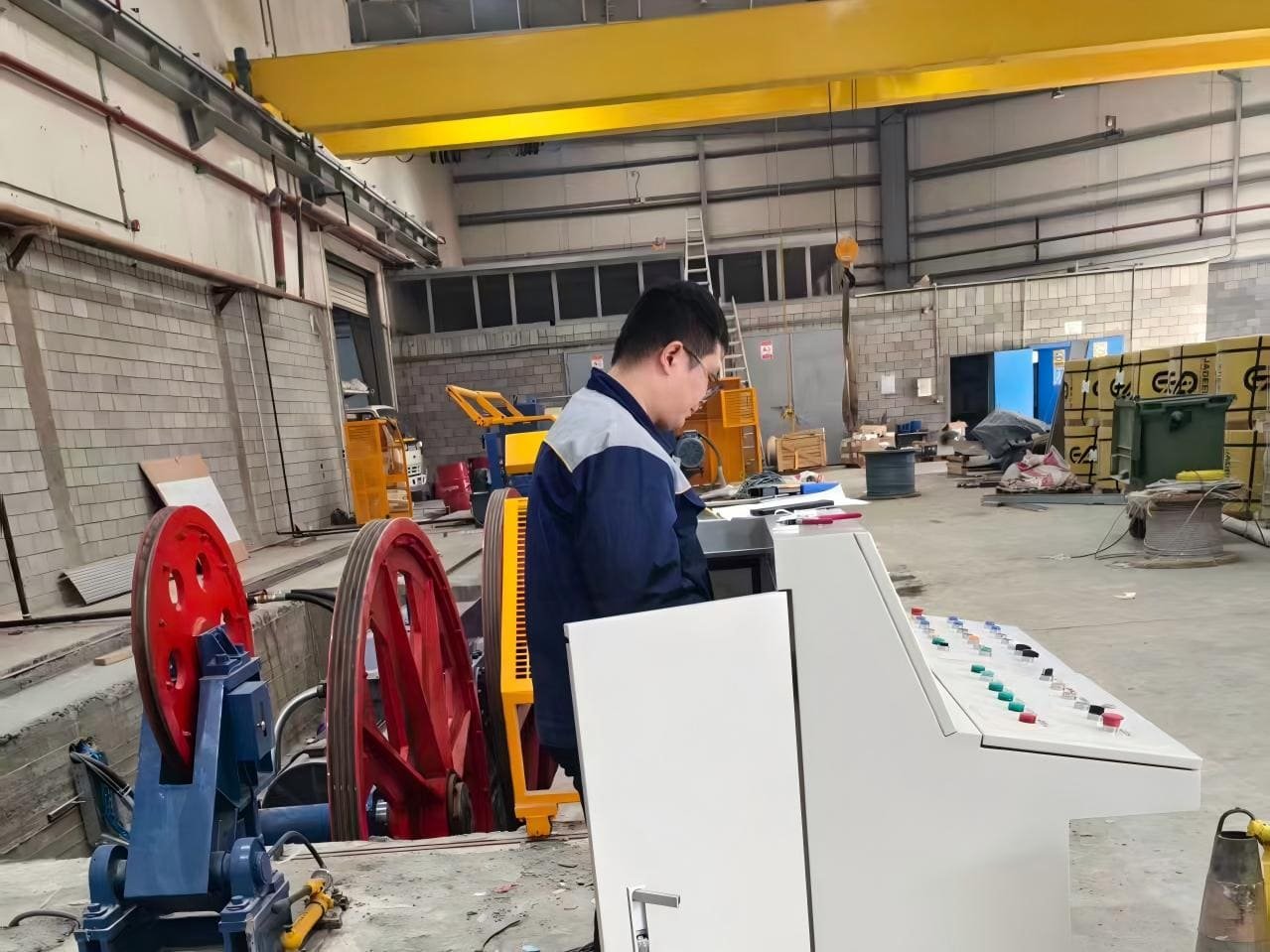 factory workers monitoring a PC strand machine control panel